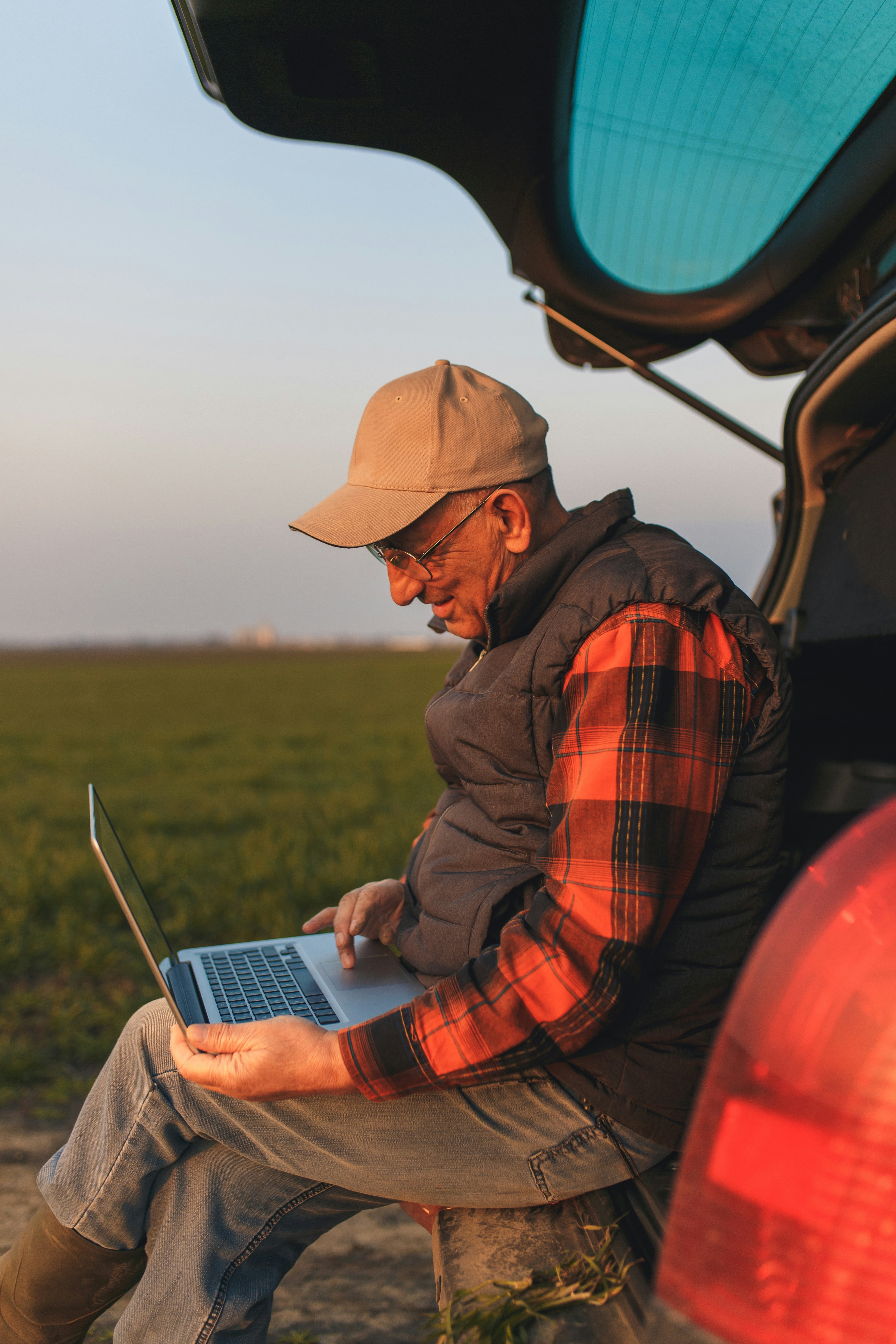 Farmer using laptop on the farm at sunset
